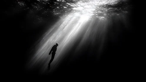 Underwater diver silhouette in high-contrast light beams.