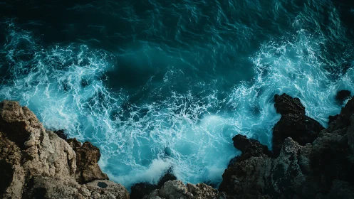 Rocky shoreline with turquoise waves under overhead view.
