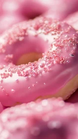 Closeup of pink frosted donuts with sparkling sugar sprinkles.