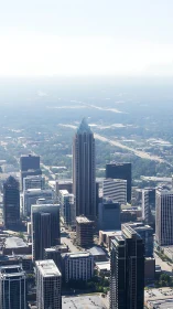 Sky piercing tower crowned in light above hazy city grid.