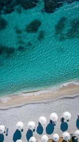 Aerial shoreline geometry with umbrellas and cyan surf