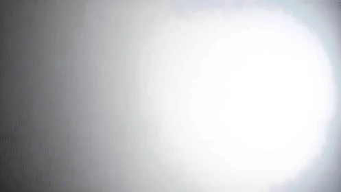 Circular overexposed light source on neutral gray surface.