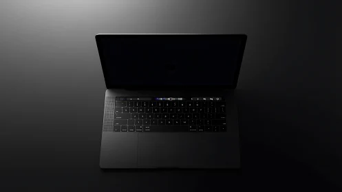 Sleek dark laptop rests in moody, minimal studio lighting.
