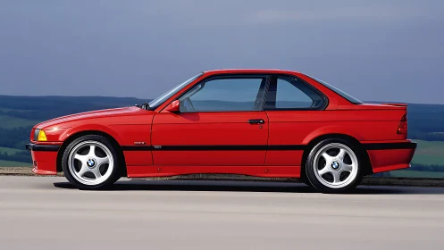 Red BMW coupe stands in profile on open road surface