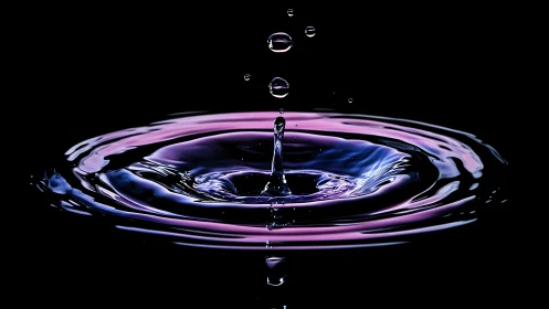 Neon water droplet impact over dark reflective surface.