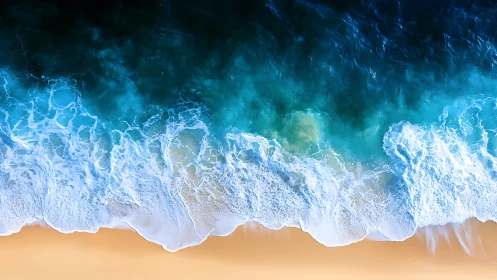 Overhead shoreline view with waves meeting sandy beach.