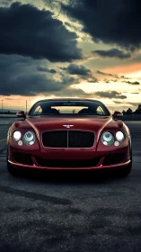 Crimson luxury coupe under brooding sunset clouds.