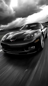 Black sports coupe storms wet racetrack under dramatic skies.