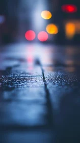 Wet urban pavement with blurred night traffic lights.