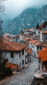 Mountain village street with stone houses and foggy peaks.