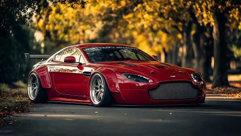 Widebody red Aston Martin on coilovers under autumn tree canopy