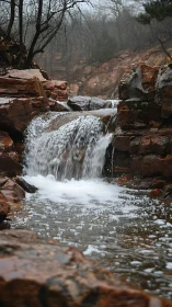 Gentle woodland waterfall over rust red canyon rocks.