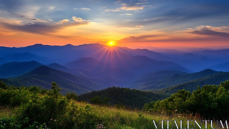Sunset descending over layered mountain ridges and valleys.
