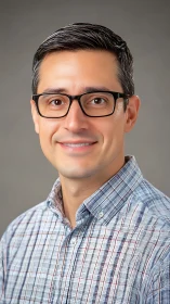 Warm portrait of a friendly man in glasses and plaid shirt.