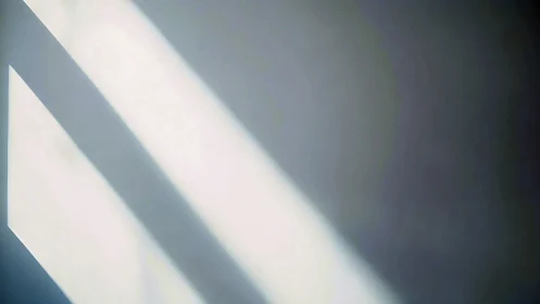 Sunlit stripes quietly slice across a softened gray wall