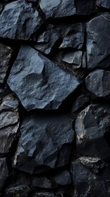 Dark fractured rock wall with angular slate surfaces.