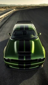 Green muscle car on open desert curve at sunset.