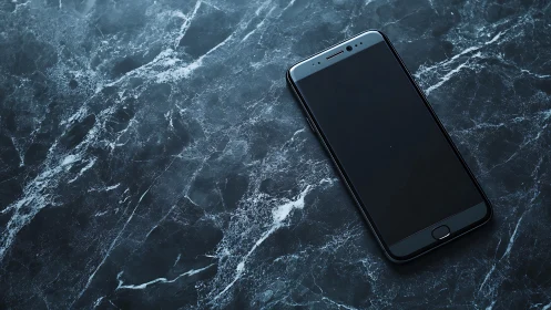 Smartphone placed on dark marble surface with white veining patterns