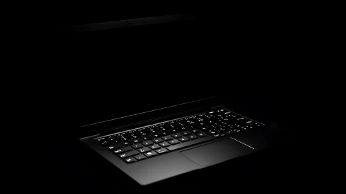 Low key photoreal laptop with illuminated keyboard in void.