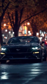 Black sports car is parked on a wet city street at night