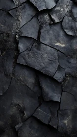 Dark fragmented stone surface with layered cracked texture.