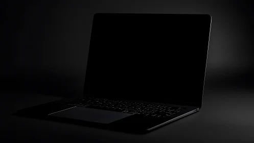 Midnight laptop waits in the dark, screen silent and sleek.