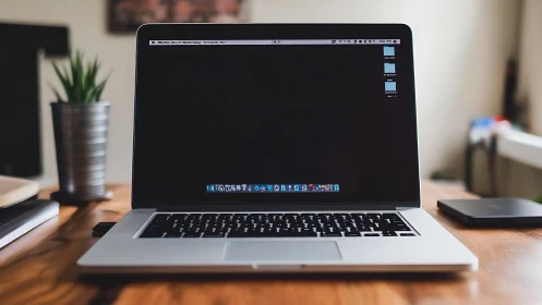 Laptop computer is positioned centrally on wooden desk surface