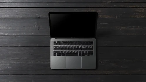 Open laptop centered on dark wooden plank surface.