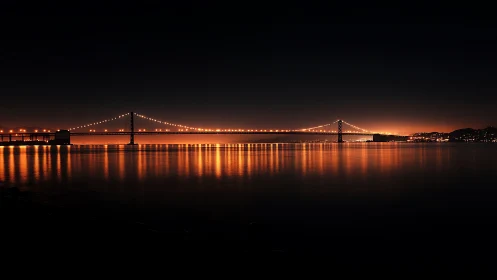 Golden bridge lights glowing softly over calm night water.