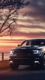 Black SUV stands on coastal road under vivid sunset sky