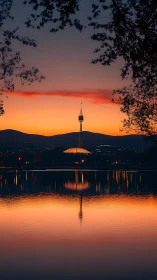 Telecommunications tower above lake at orange dusk horizon.