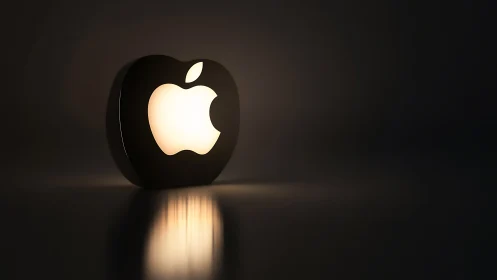 Glowing Apple Logo Lamp Against Dark Background. Illuminated Design Object.