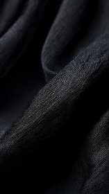 Textural study of folded black textile in macro detail.