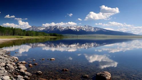 Snow-capped mountain range reflected in calm lake surface.