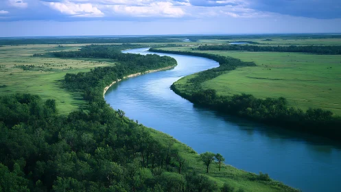 Meandering river cuts through verdant floodplain under stormfront