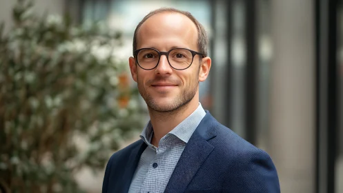 Calm professional in navy blazer under soft city daylight.