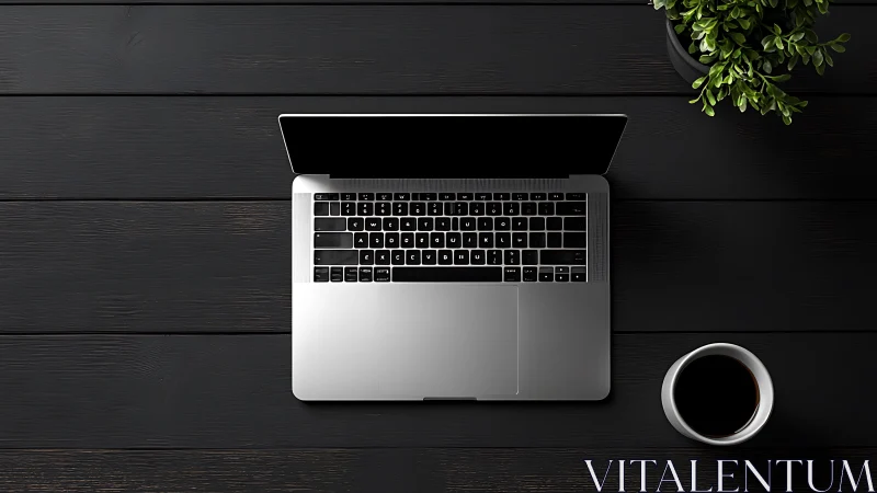 Minimalist silver laptop on dark desk with coffee and plant.