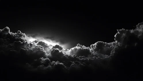 Backlit cumulonimbus cloud bank in monochrome night sky.