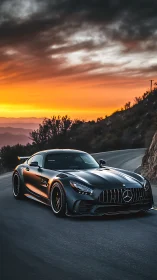 Black Mercedes sports car on winding mountain road at sunset.