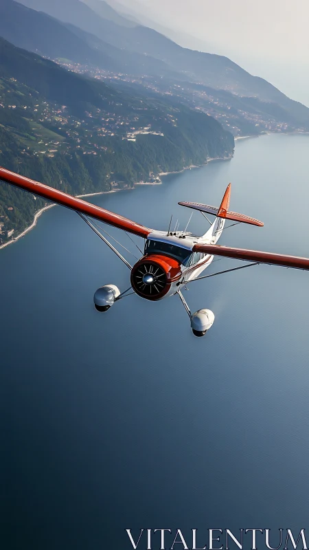 Vintage seaplane glides above tranquil coastal lake shoreline.