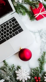 Laptop workspace with red Christmas ornament and gift