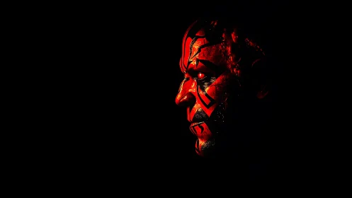 Red painted male face in harsh side light on black background.