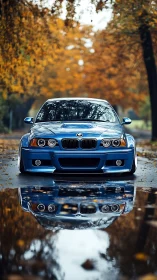 Autumn alley reflections with vivid blue sports sedan front.