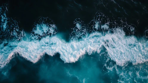 Breaking teal waves roll across a deep midnight ocean