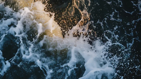 Turbulent seawater surface captures foamy wake and golden spray