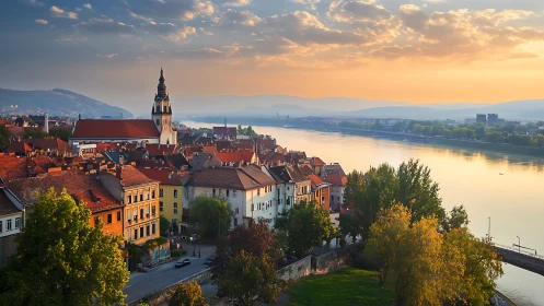 Riverfront European town under warm evening sunset glow.
