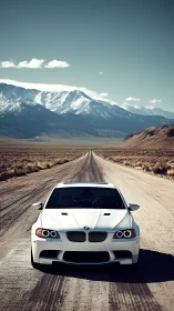 White BMW sedan parked on remote desert highway at mountains.