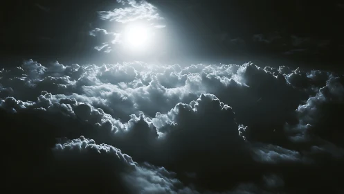 Luminous moon above stormy clouds in monochrome nightscape.