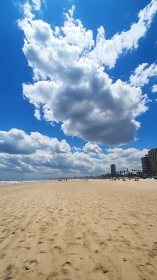 Clouds build above wide sandy beach with distant cityline