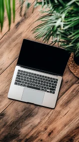 Silver laptop rests on rustic wooden desk beside plant